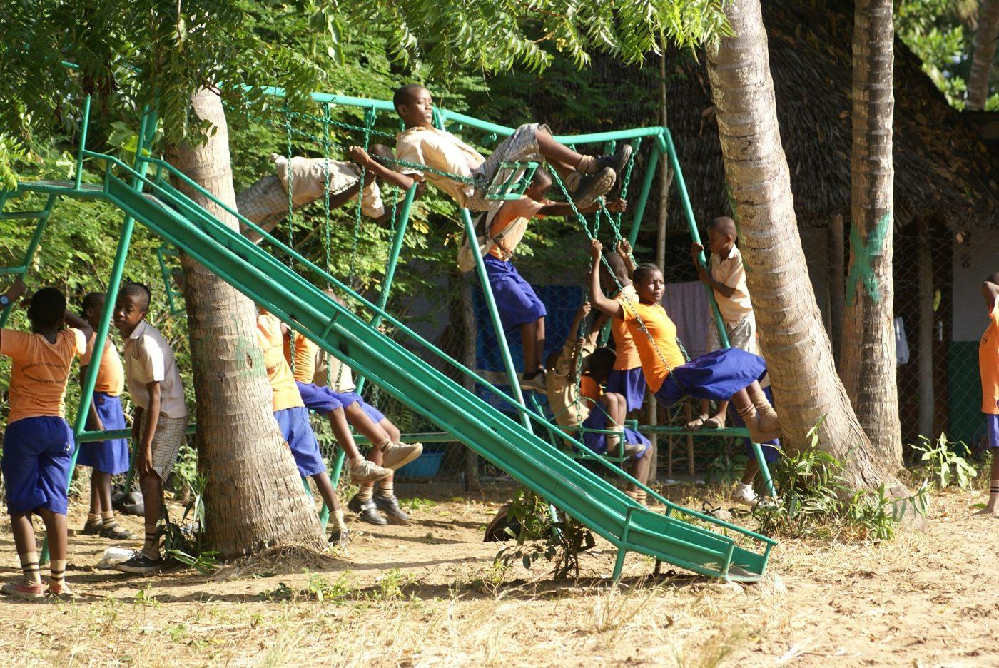 Kinder auf Schaukel und Rutsche in der Pause
