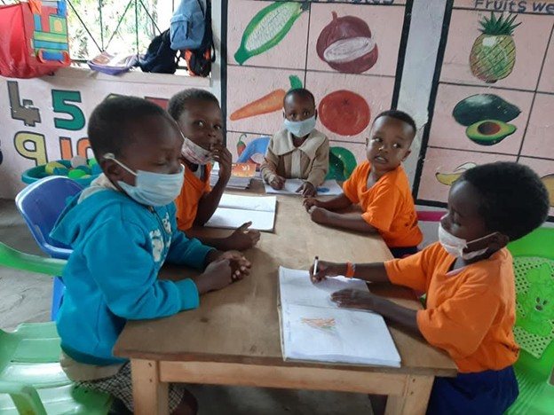 Kindergartenkinder mit Masken beim Unterricht