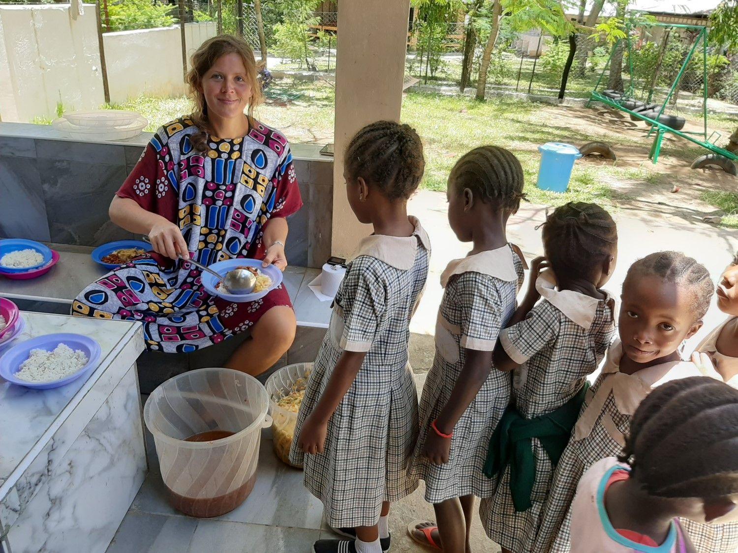 Volontärin teilt das Mittagessen an Kindergartenkinder aus