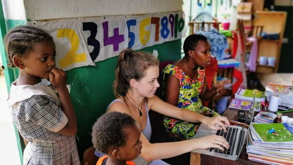 Eine Volontärin arbeitet mit einer Lehrerin am Laptop